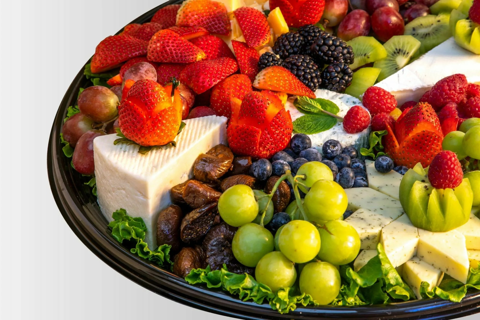 variety of fruit and cheeses on a black platter