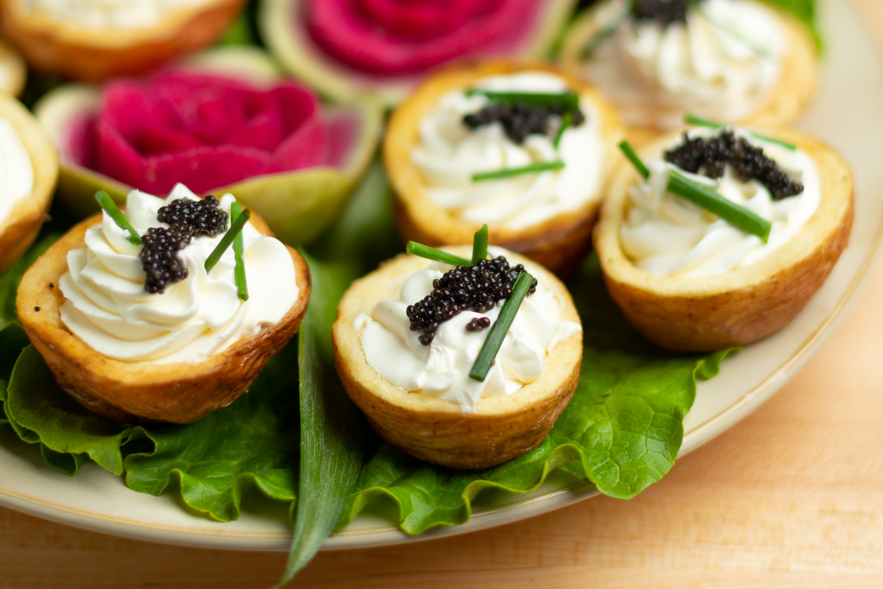 baby potatoes with creme fraiche in middle topped with caviar on a white plate